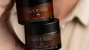 Imagem fechada dos hidratantes faciais Nooskin, Daylight Vitality e Moonlight Repair, na mão de um homem. Os potes estão um sobre o outro.