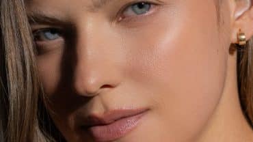 Imagem fechada no rosto de uma mulher de olhos claros, cabelos castanhos e pele levemente bronzeada.